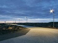 Дорожні та вуличні ліхтарі в сутінках з хмарним небом — стокове фото