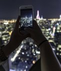 Жіночих рук з смартфон, приймаючи фото ніч запалили Нью-Йорк міський пейзаж — стокове фото