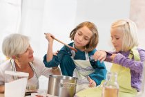 Girls with grandmother cooking jam — Stock Photo