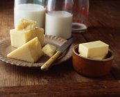 Fromage, beurre et bouteilles de lait sur table en bois — Photo de stock