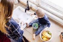 Vista aérea de la mujer en el fregadero de la cocina con bebé hijo - foto de stock