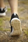 Vista trasera recortada de los pies de las mujeres que usan zapatos de correr - foto de stock
