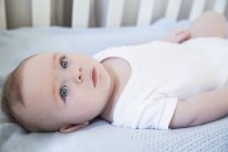 Blue eyed baby boy lying in his crib — Stock Photo