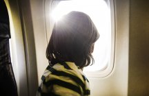 Хлопчик на літак, переглядаючи сонячної літак вікно — стокове фото