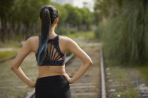 Rear view of woman on railway track, hands on hips — Stock Photo