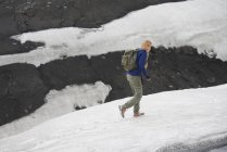 Hiker walking on snowy hillside — Stock Photo
