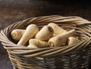 Fresh baby parsnips in wicker basket — Stock Photo