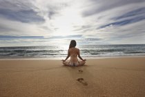 Woman meditating on sandy beach — Stock Photo