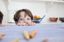 Young boy peering over kitchen work surface — Stock Photo