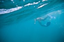Frau in Flossen schwimmt im Ozean — Stockfoto