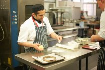 Chef docente dimostrando tecnica per adolescente studente di catering al bancone della cucina — Foto stock