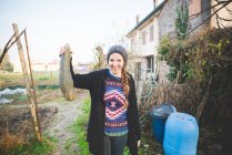 Junge Frau im Garten hält Knochenmark-Kürbis in die Kamera und lächelt — Stockfoto