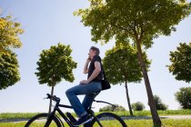 Человек разговаривает по мобильному телефону на велосипеде — стоковое фото