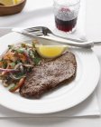 Steak mit roten Zwiebeln, weißen Bohnen, Tomaten, Petersilie und Zitronenscheibe — Stockfoto