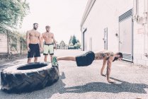 Young male cross trainer doing push-ups from tyre outside gym — Stock Photo