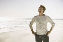 Зрілий чоловік стоїть на пляжі, дивлячись на відстань — стокове фото