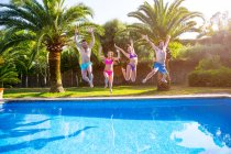 Amigos pulando na piscina — Fotografia de Stock