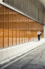 Бизнесмен выходит из офисного здания возле стены — стоковое фото