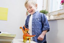 Ragazzo che gioca con dinosauri giocattolo a casa — Foto stock