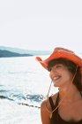 Donna sorridente che indossa il cappello da sole sulla spiaggia — Foto stock