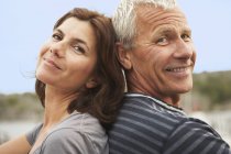 Middle aged couple, back to back, smiles — Stock Photo