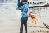 Joven llevando novia al revés en la orilla del lago, Lago de Como, Italia - foto de stock