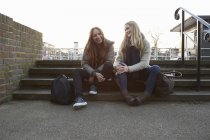 Due amiche sedute sui gradini e sorridenti — Foto stock