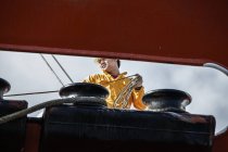 Worker fastening ropes to mooring posts on board oil tanker — Stock Photo
