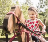 Ragazza su cavallo hobby di legno sorridente — Foto stock