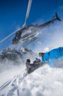 Elicottero in partenza da snowboarder maschi in montagna, Trento, Alpi svizzere, Svizzera — Foto stock