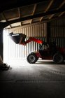 Farmer driving digger in shed — Stock Photo