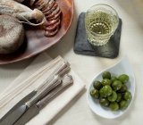 Стакан белого вина, зеленые оливки и салями подается на стол — стоковое фото
