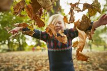 Ragazza gettando in foglie di autunno — Foto stock