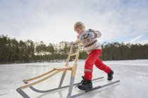 Menino empurrando kicksled através do lago congelado, Gavle, Suécia — Fotografia de Stock