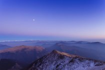 Заснеженный горный пейзаж с туманом долины на рассвете — стоковое фото