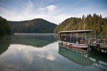 Ferryboat em doca de madeira em lago imóvel — Fotografia de Stock