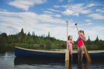 Two little sisters chatting next to canoe on Indian River, Ontario, Canada — стоковое фото