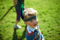 Retrato de menino vestindo faixa de cabeça com penas — Fotografia de Stock