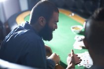 Par-dessus la vue d'épaule des hommes jouant au jeu de cartes à table de pub — Photo de stock