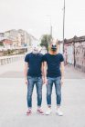 Portrait of two men wearing rabbit and horse masks on urban bridge — Stock Photo