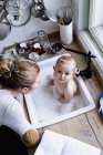 Overhead portrait of baby boy bathing in kitchen sink — Stock Photo
