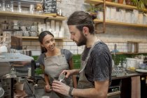 Male and female baristas preparing coffee in cafe — Stock Photo