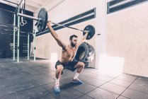 Young man weightlifting barbell in cross training gym — Stock Photo