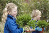 Ecole garçon et fille avec des plantes dans le jardin — Photo de stock