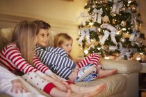 Boy and girls in striped pyjamas on sofa at christmas — Stock Photo