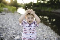 Portrait de mignon garçon tenant des bâtons sur sa tête au lac Ontario, Oshawa, Canada — Photo de stock