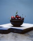 Close up of Cherries in bowl on rustic chopping board — Stock Photo