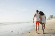 Vue arrière d'un jeune couple romantique se promenant sur la plage — Photo de stock