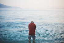 Hombre con la cabeza abajo de pie en el lago de Garda, Italia - foto de stock
