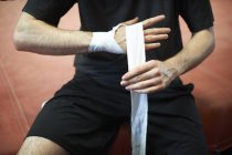 Boxer bandaging hands before putting on gloves, mid section — Stock Photo